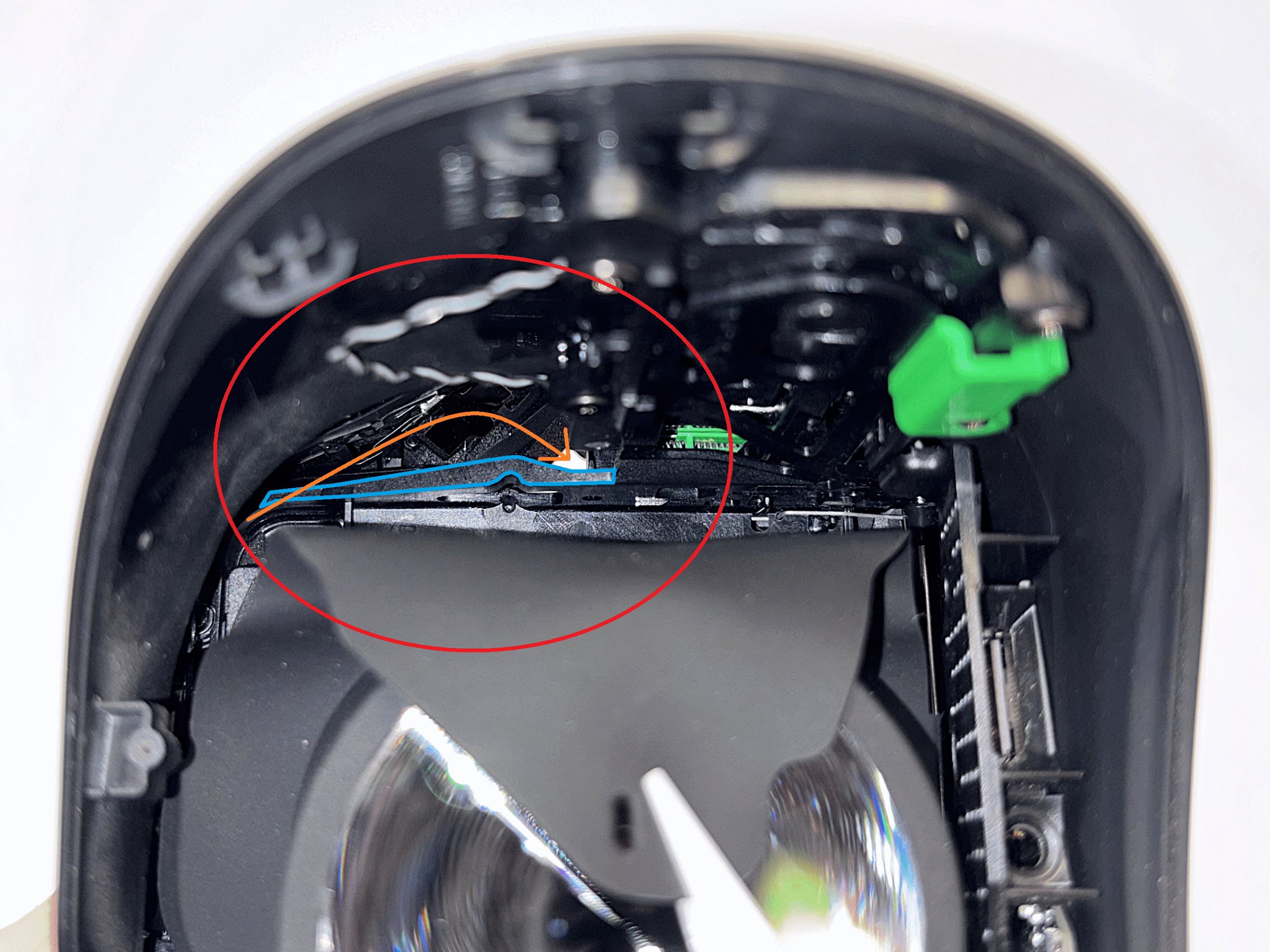 Reference image showing blue-marked plastic piece and orange arrow for cable routing